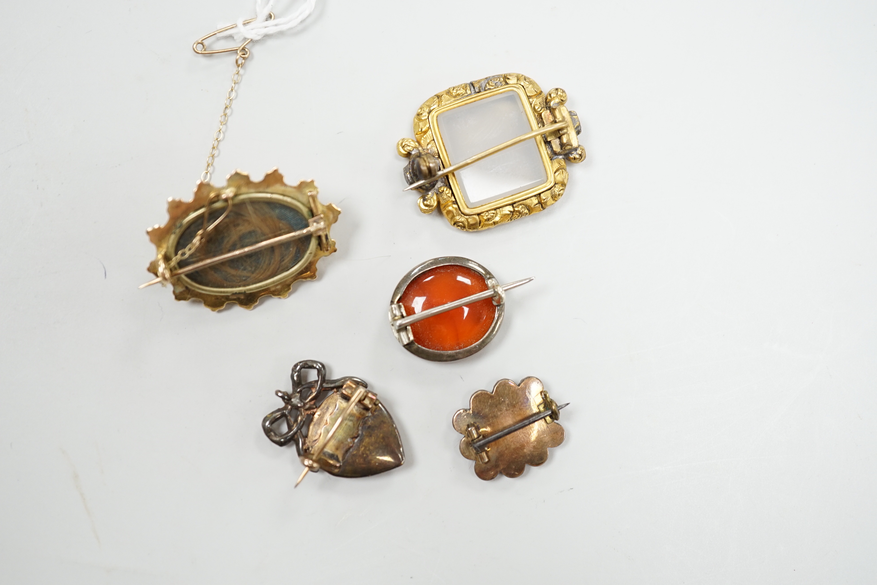 Five assorted antique brooches, comprising an early 19th century foiled ruby and hair work heart shaped brooch, 2.25cm, an early 19th century foiled garnet memorial brooch, 1.75cm, a Victorian unmarked gold oval brooch,